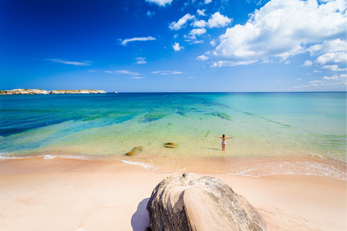 yoga-Retreat-Stephanie-Muley-portugal Eine Frau steht am Stand im Meer und streckt beide Arme von sich