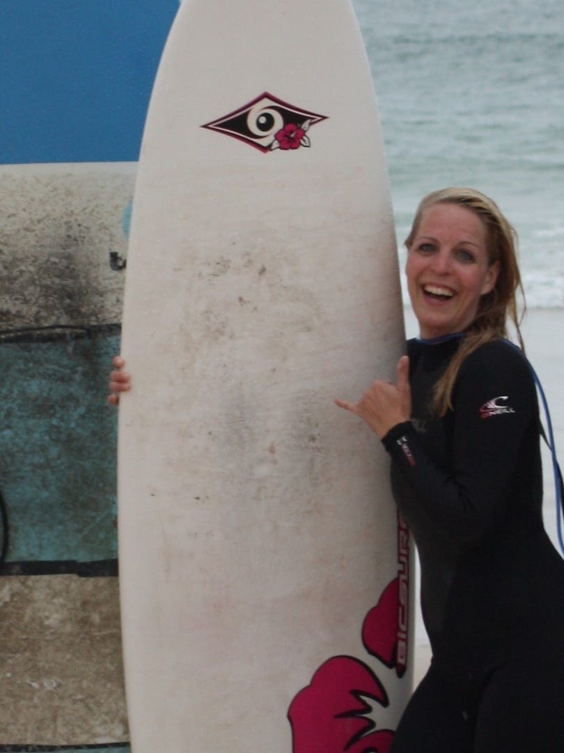 Steffi von Aloha Lifestyle mit Ihrem Surfbrett im Hintergrund sieht man das Meer